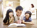 Asian father and children reading book together Royalty Free Stock Photo