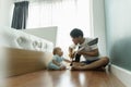 Asian Father and Cute little boy son sitting on wood floor singing and playing acoustic guitar together Royalty Free Stock Photo