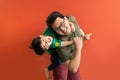 Asian father giving son ride on the back with a red background. Portrait of a happy father giving son piggyback a ride on his Royalty Free Stock Photo