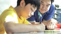 Asian father helping her son doing homework on white table Royalty Free Stock Photo