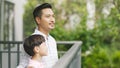 Asian father and his son standing on balcony enjoying fresh nature