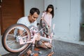 Asian father holding bicycle frame and daughter carrying wheels Royalty Free Stock Photo