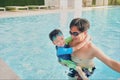 Asian Father holding cute little Asian toddler boy child at swimming pool in sunny day, Happy dad and son spending time together Royalty Free Stock Photo