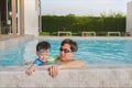 Asian Father holding cute little Asian toddler boy child on the edge of a swimming pool, Happy dad and son spending time together Royalty Free Stock Photo