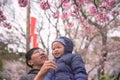 Asian father holding his cute little 2 - 3 years old toddler boy son in blossom spring public garden sightseeing sakura or cherry