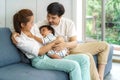 Asian father and mother are hugging 9 months baby son on sofa. They are smiling and warm touching to the baby with love in living Royalty Free Stock Photo