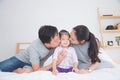 Father and mother kissing their daughter on bed Royalty Free Stock Photo