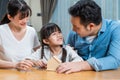 Asian Father and Mother teach young daughter to save money for future. Happy little girl enjoy put coins in piggy bank with