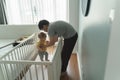 Asian Father putting his litte baby into crib in bedroom