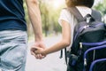 Asian father`s hand lead his girl child in summer park go to sch