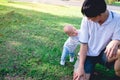 Asian Father and smiling son play peekaboo in the park in the sunshine morning with copy space Royalty Free Stock Photo