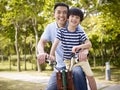 Asian father and son enjoying biking outdoors