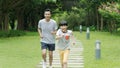 Asian father & son smiling & running in park in summer