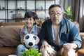 Asian father and son watching football sports games on TV and reacting happy exiting when team Shoot the ball into the goal.