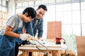 Asian father and son work as a woodworker or carpenter, Father teaches his son to saw a wooden plank with hack saw carefully Royalty Free Stock Photo