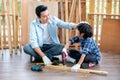 Asian father touch head of his son during drill the timber in home workplace of carpentering with happy emotion. Asian family Royalty Free Stock Photo