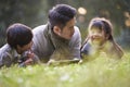 Asian father and two children relaxing outdoors in city park Royalty Free Stock Photo