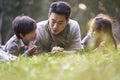 Asian father and two children relaxing outdoors in city park Royalty Free Stock Photo