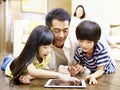 Asian father and two children using digital tablet together Royalty Free Stock Photo