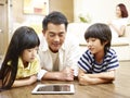 Asian father and two children using digital tablet together Royalty Free Stock Photo