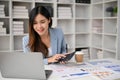 An Asian female accountant examining financial report, calculating business monthly expenses