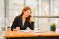 Asian female accountant working on paperwork at office while talking on the phone Royalty Free Stock Photo