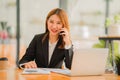Asian female accountant working on paperwork at office while talking on the phone Royalty Free Stock Photo