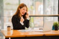 Asian female accountant working on paperwork at office while talking on the phone Royalty Free Stock Photo