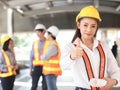 Asian Female architect or engineer holding blue print paper, standing in front of her team smiling , looking at camera and Royalty Free Stock Photo