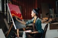 Asian Female Artist Draws create art piece with palette and brush painting at studio. Royalty Free Stock Photo