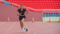 Asian female athlete accelerates during her speed running practice on the stadium track, embodying determination Royalty Free Stock Photo