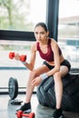 asian female athlete with dumbbell sitting on training tire