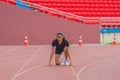 Asian female athlete at start block, ready for her speed running practice on the stadium track, epitomizing readiness Royalty Free Stock Photo