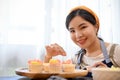 Asian female baker decorating her beautiful homemade cupcake with tiny white chocolate ball Royalty Free Stock Photo