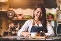 Asian female barista making cup of coffee. Young woman holding white coffee cup while standing behind cafe counter bar in Royalty Free Stock Photo
