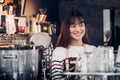 Asian female barista wear jean apron at counter bar with smile face, cafe service concept, owner business start up