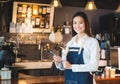 Asian female barista wear jean apron hold tablet computer coffee