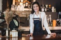 Asian female barista wear jean apron place her hand on counter b
