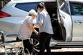 Asian female caregiver helping disabled elderly woman in wheelchair to get into the car,helpful daughter care and support senior