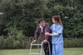 Asian female caregiver helps senior man walk A senior using a walker is assisted by a nurse at home. A nurse helps an Royalty Free Stock Photo