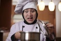 Asian female chef open cooking pot and smelling food aroma that she cooked, bad worried face expression