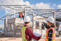 Asian female civil engineer architect and male contractor wear hard hat standing hold blueprint and pointing while checking Royalty Free Stock Photo