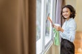 asian female cleaning staff smiling while wiping windows