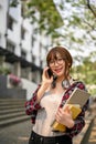 Asian female college student talking on the phone while standing outside of the campus building Royalty Free Stock Photo