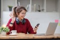 Asian female college student using laptop and phone with headphones while studying. Reading messages and greeting Royalty Free Stock Photo