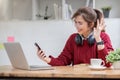 Asian female college student using laptop and phone with headphones while studying. Reading messages and greeting Royalty Free Stock Photo