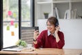 Asian female college student using laptop and phone with headphones while studying. Reading messages and greeting Royalty Free Stock Photo