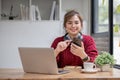 Asian female college student using laptop and phone with headphones while studying. Reading messages and greeting Royalty Free Stock Photo