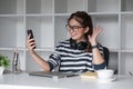 Asian female college student using laptop and phone with headphones while studying. Reading messages and greeting Royalty Free Stock Photo