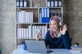 Asian female college student wearing headphones studying online using mobile smartphone app contacting laptop